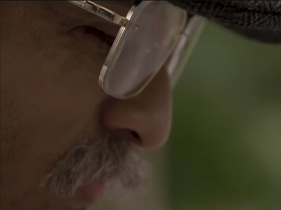 A close-up still image from the film 'Reflections' of a man's face highlighting make-up work that has significantly aged the actor's appearance with a focus on the eyes and facial hair